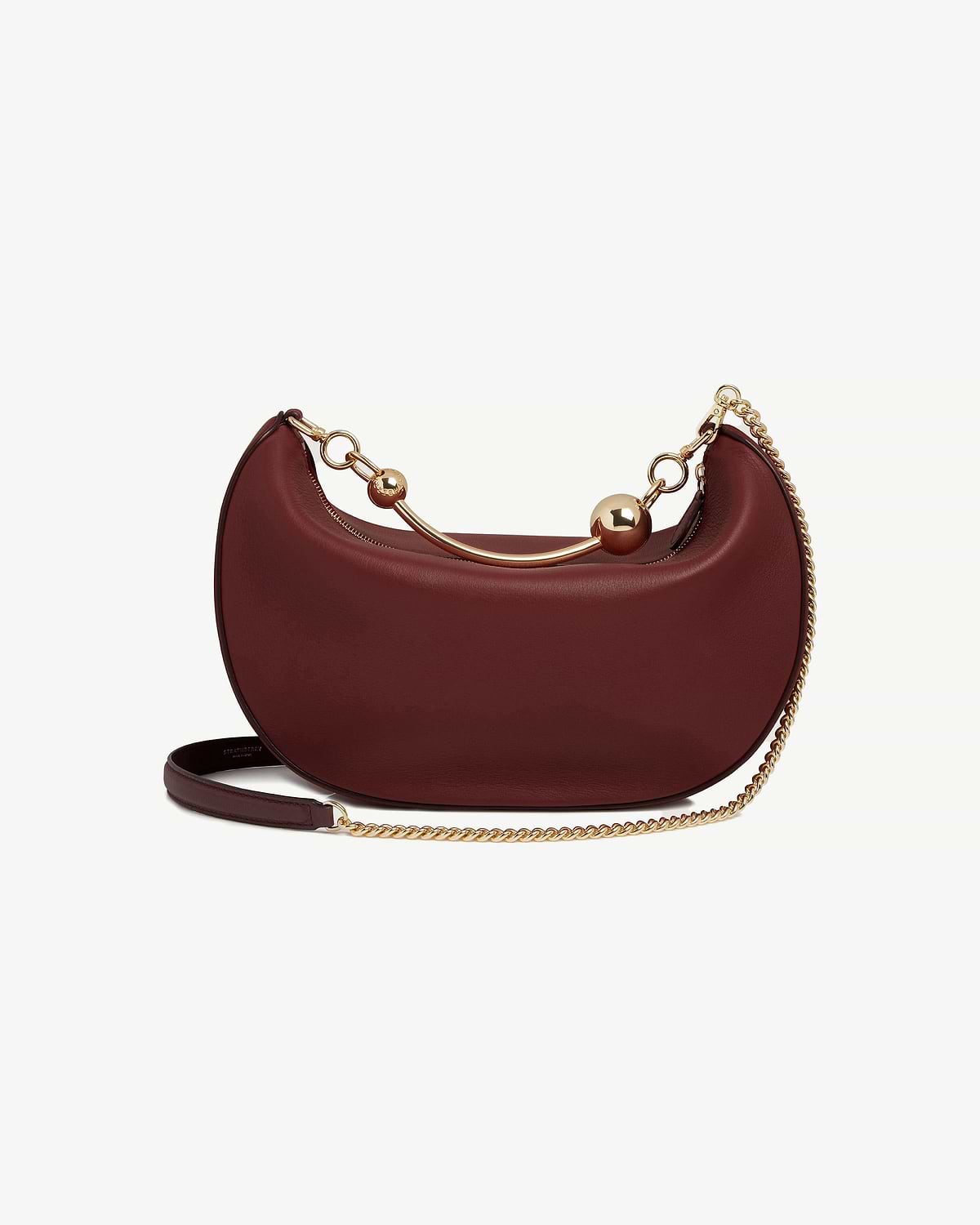 Oxblood crescent-shaped leather shoulder bag with gold chain and sphere accents.