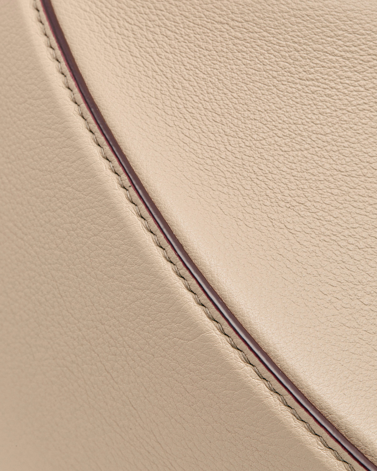 Oat-coloured leather crescent moon bag showing stitching and contrast edge piping