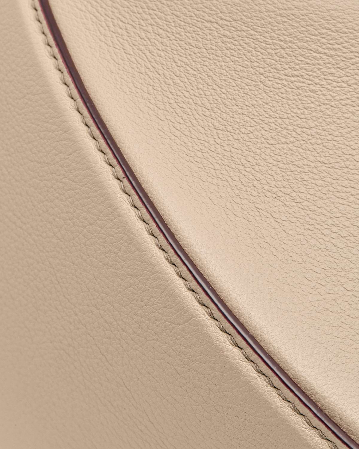 Oat-coloured leather crescent moon bag showing stitching and contrast edge piping