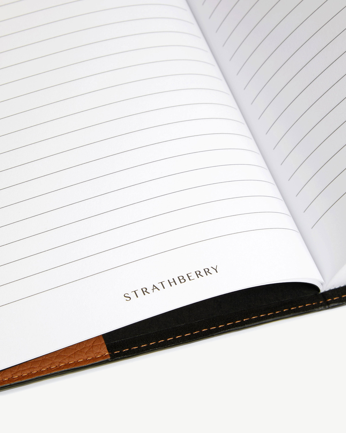 Open lined notebook pages showing STRATHBERRY logo and tan leather spine.