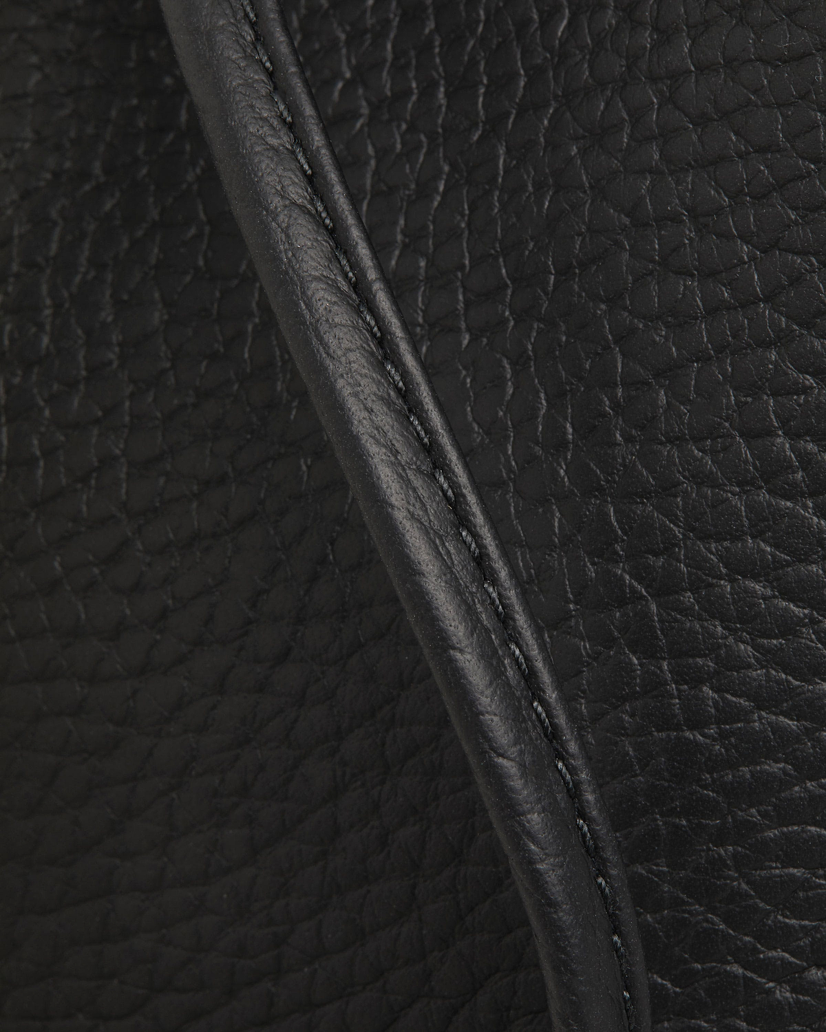 Black pebbled leather with stitched piping, folded edge and visible grain texture.