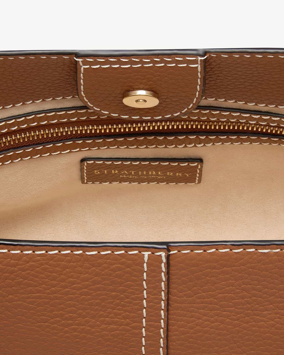 Tan pebbled leather interior with white stitching, gold zip and Strathberry label.