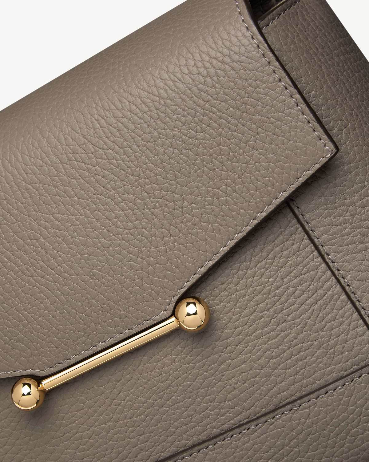 Taupe pebbled leather bag flap with gold bar and spherical end hardware
