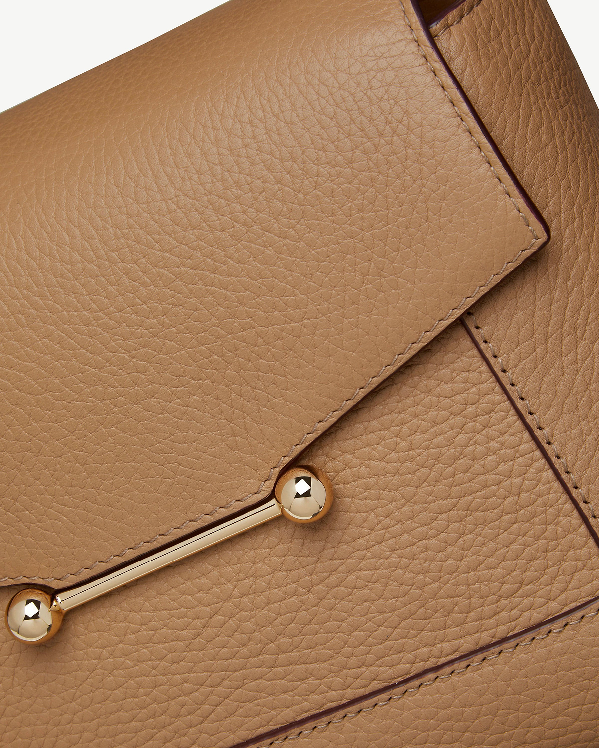 Close-up of caramel pebbled leather mosaic bag showing gold bar hardware.