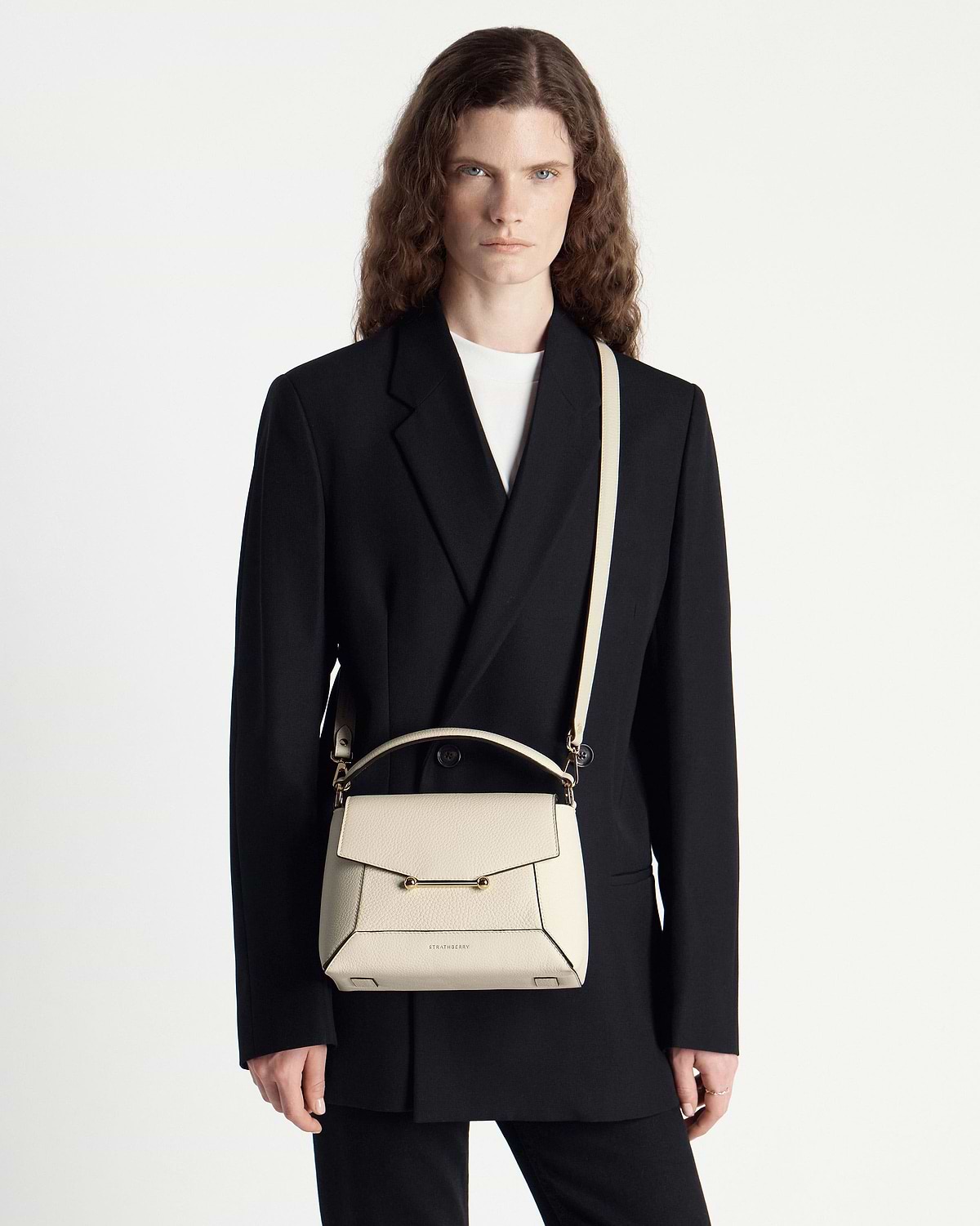 Model wearing black blazer with a vanilla Strathberry mosaic bag worn crossbody.