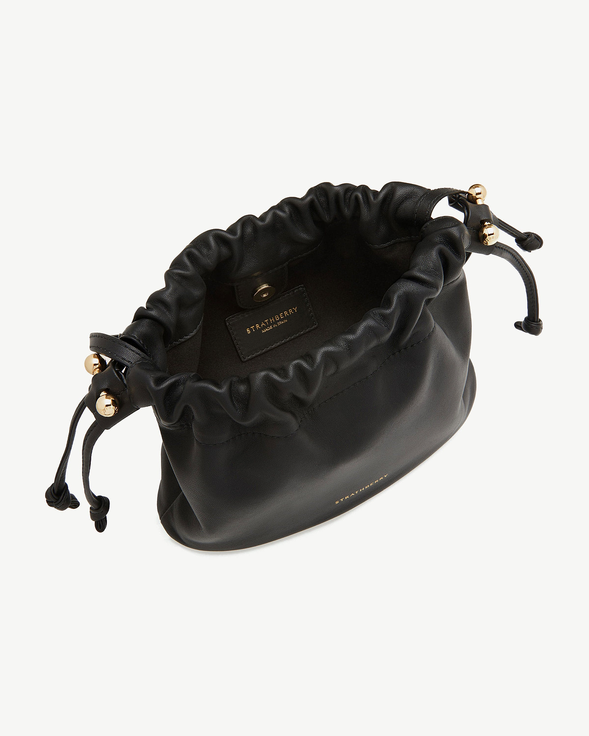 Strathberry Charlotte drawstring bag, black leather with gold hardware, open top.