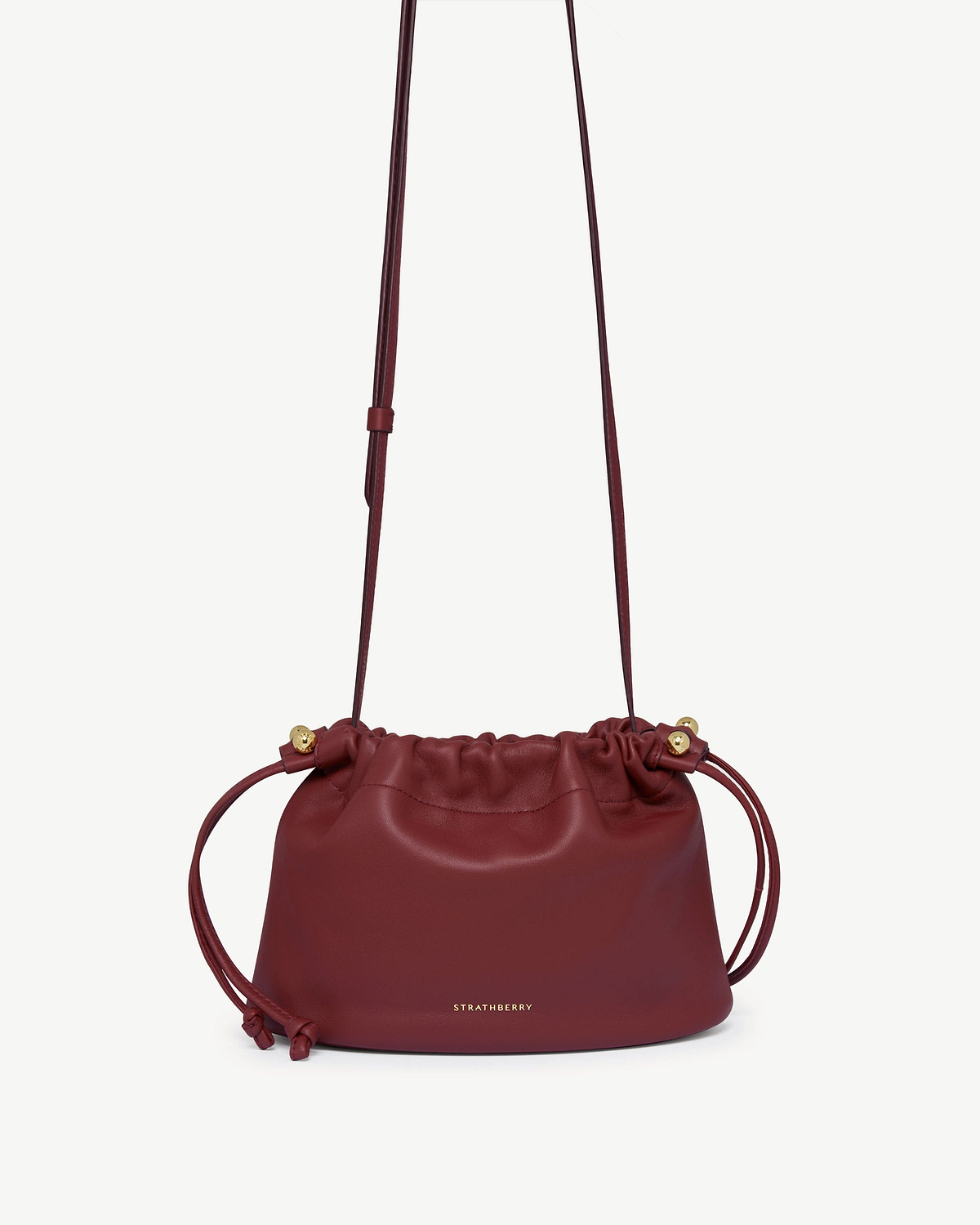 Oxblood Strathberry Charlotte drawstring bag with long strap and gold fittings.