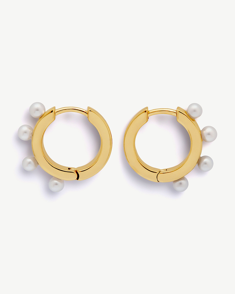Pair of 22 carat gold-gilded huggie hoop earrings with white pearl embellishments.