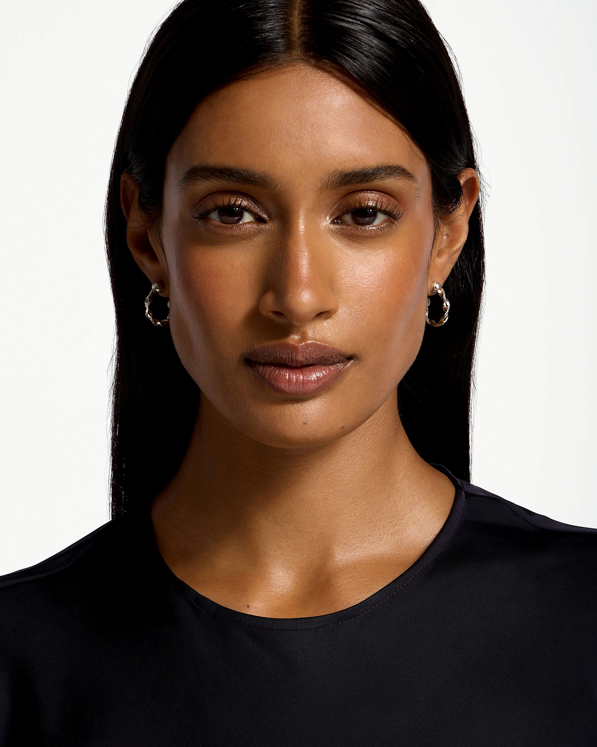 Model wearing sterling silver crescent twisted hoop earrings against white background