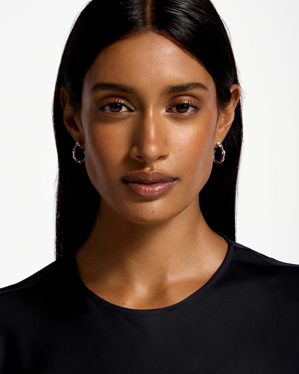 Model wearing sterling silver crescent twisted hoop earrings against white background