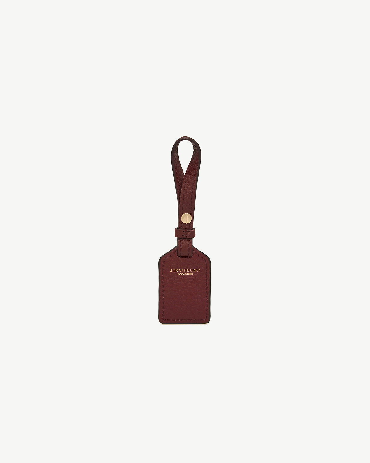 Oxblood leather luggage tag with strap and gold Strathberry logo.