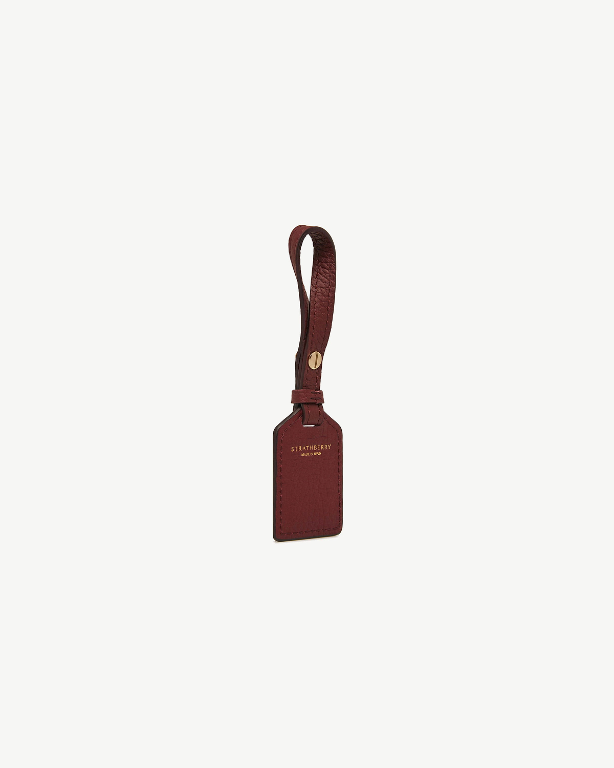 Oxblood leather tag with Strathberry gold logo and leather strap.