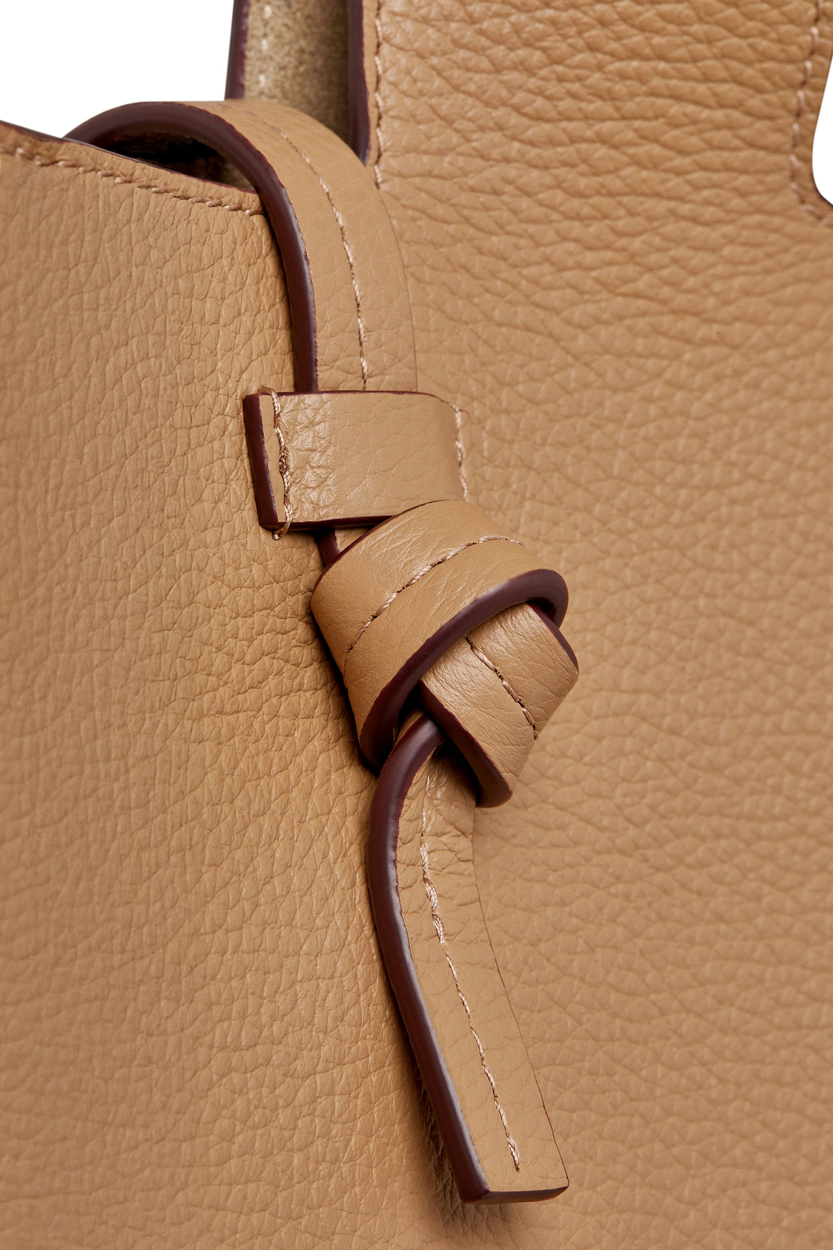 Caramel leather tote knot and strap detail with pebbled texture.