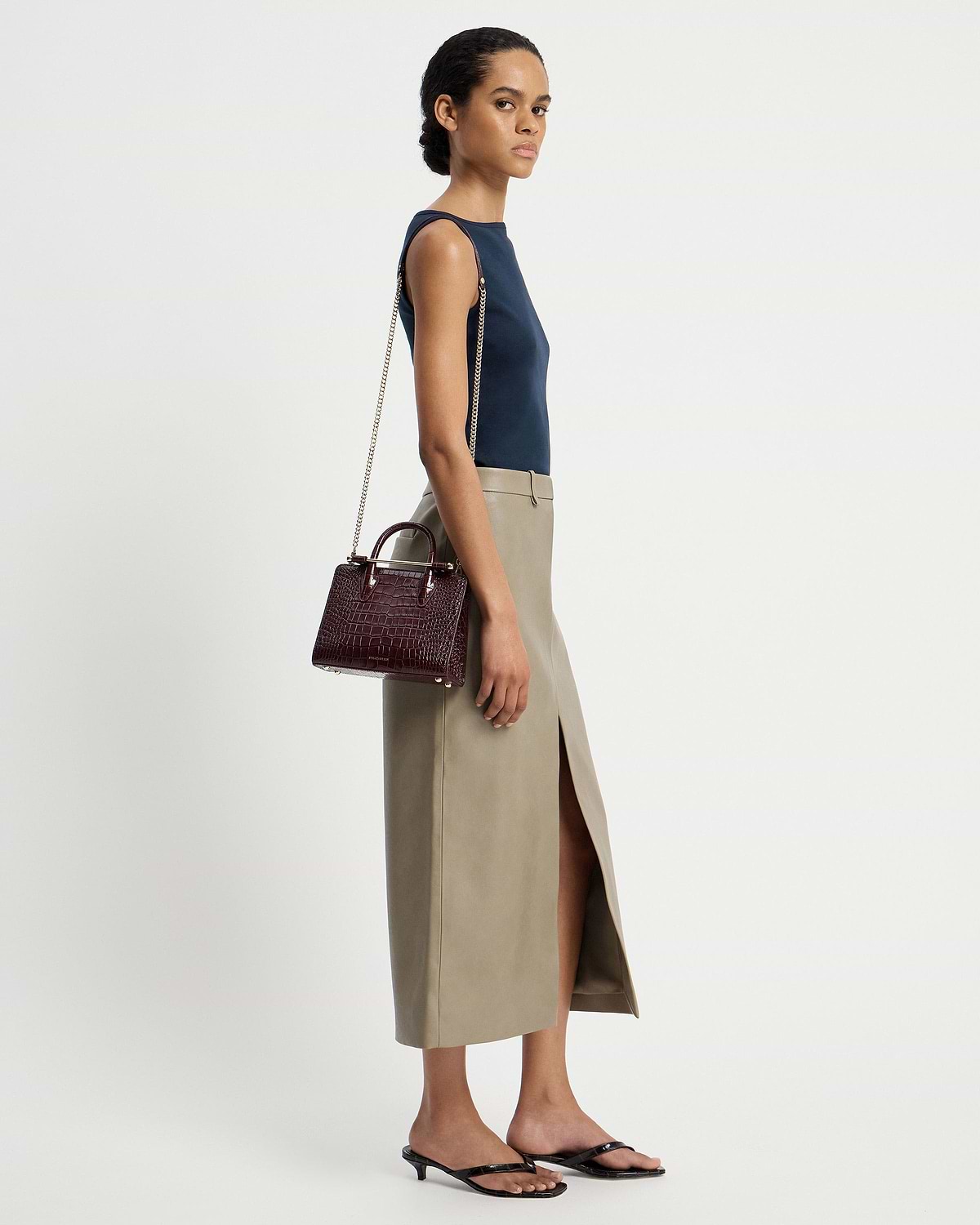 Model wearing a croc mini tote with chain strap over her shoulder.