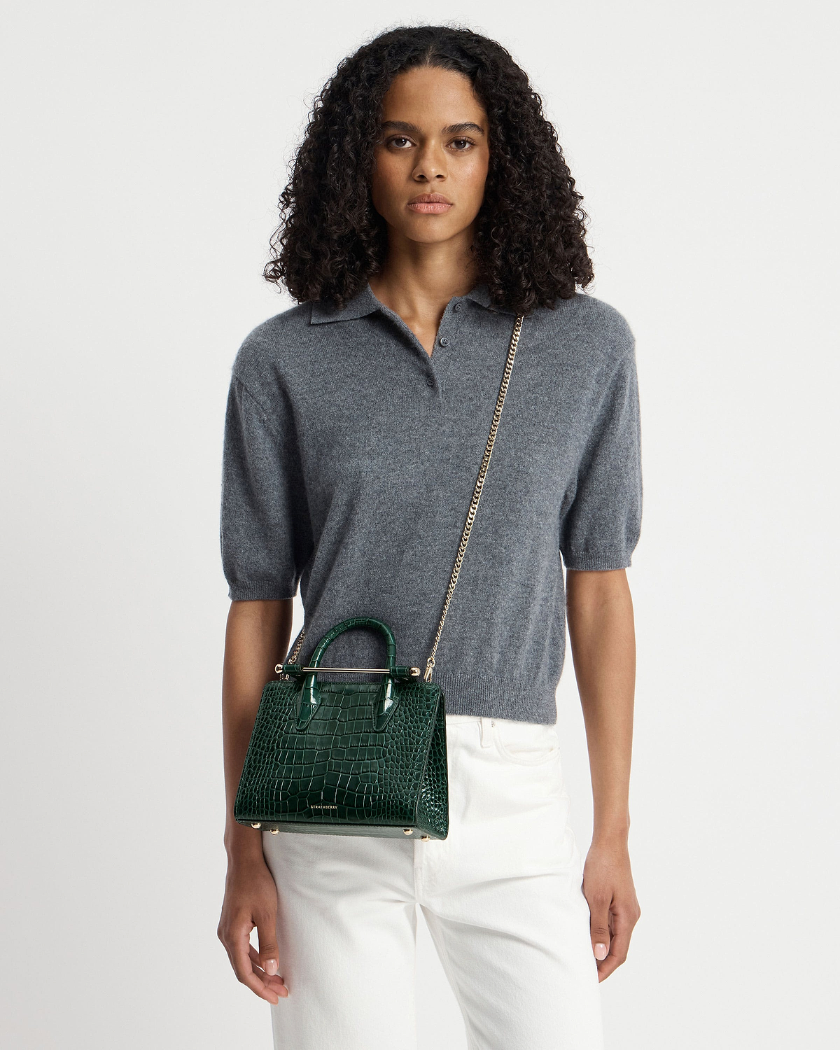Model wearing grey top with Strathberry green croc mini tote and chain strap.