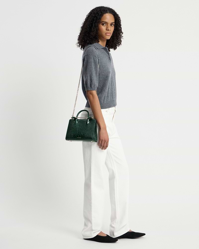Model wearing a green croc mini tote with chain shoulder strap.