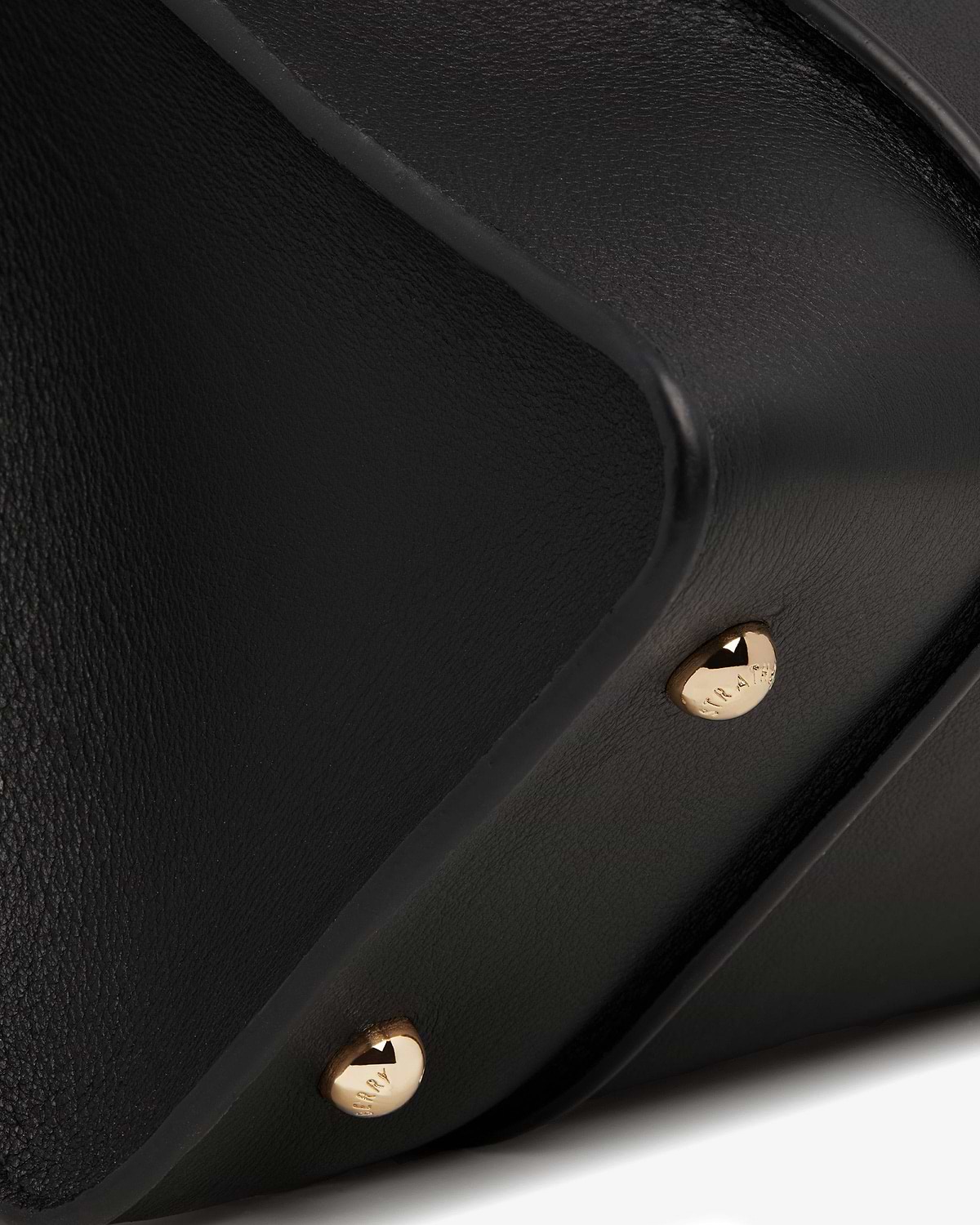 Close-up of black bag corner with gold studs and pebbled leather texture