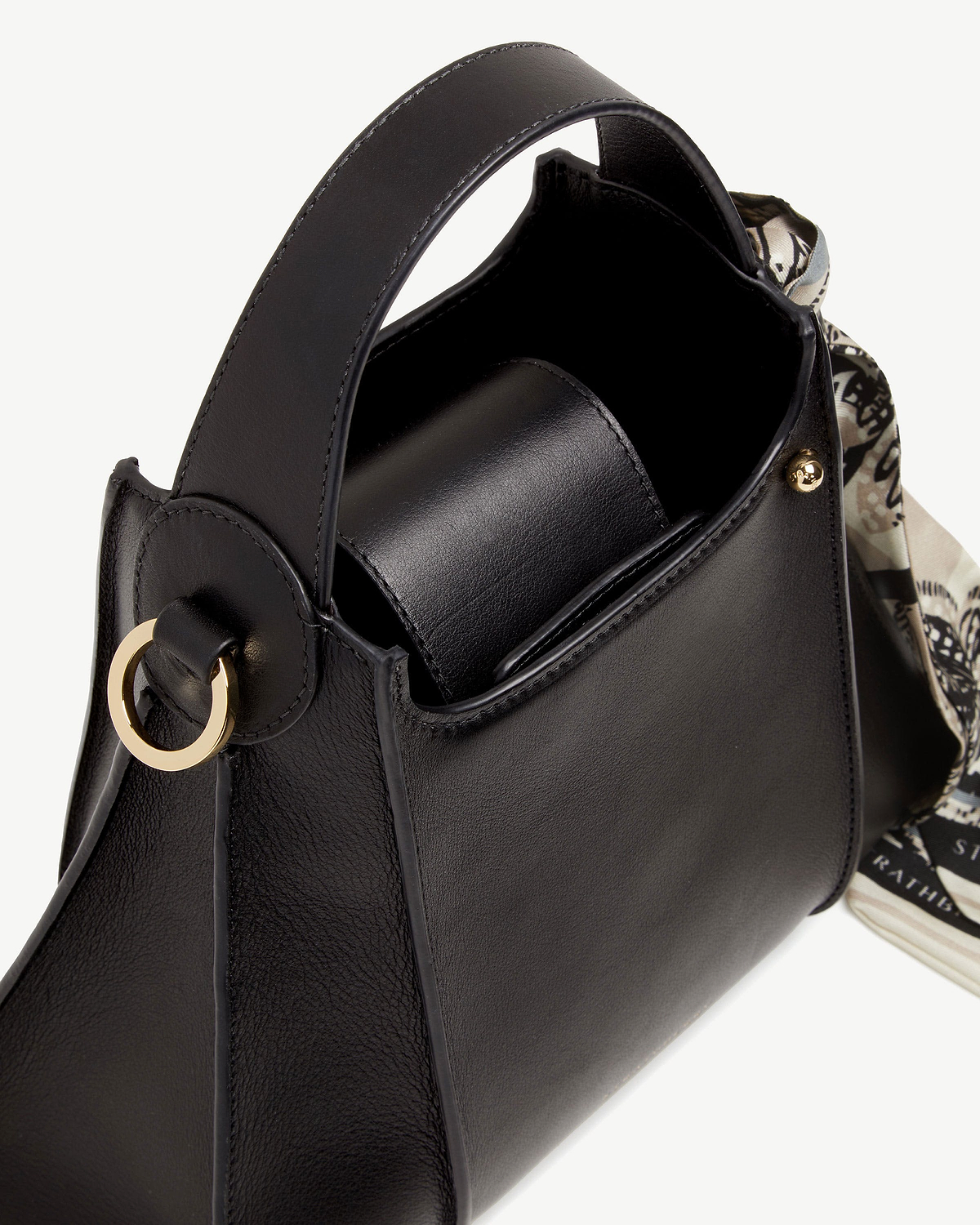Black Arkshell leather handbag with top handle, gold ring and patterned scarf.