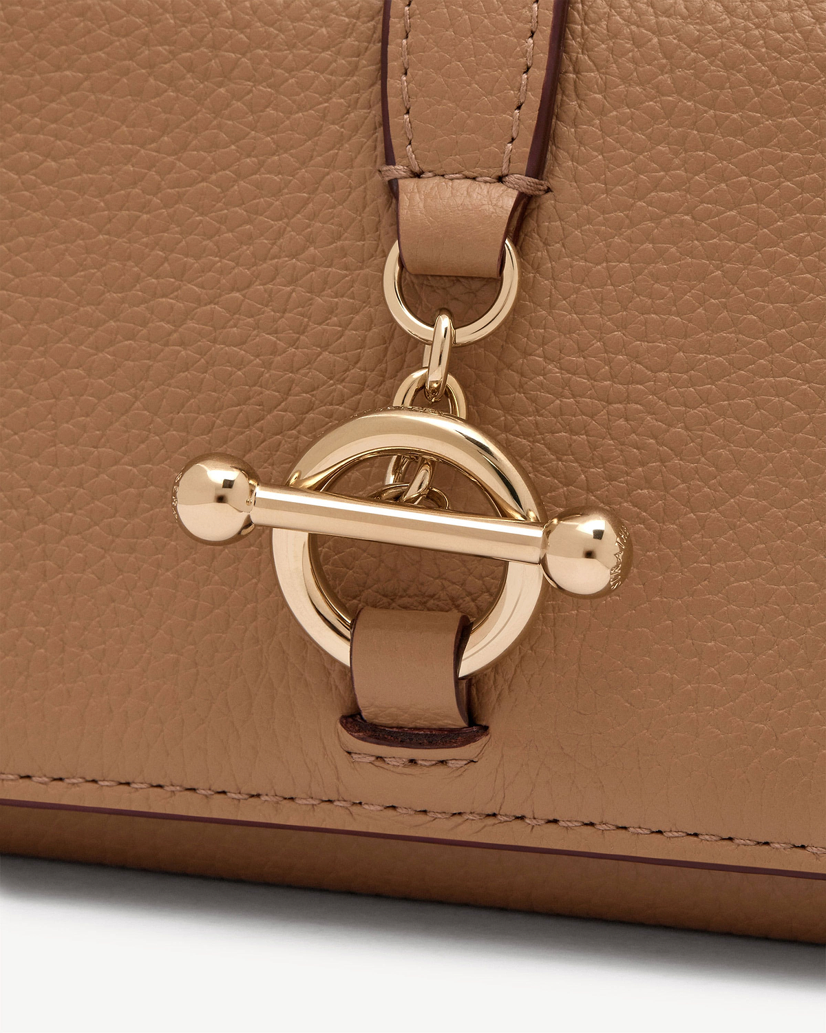 Close-up of caramel pebbled leather with gold toggle clasp on wallet.