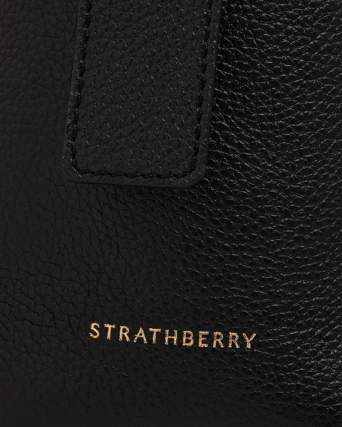 Black pebbled leather with stitched tab and gold Strathberry logo visible.