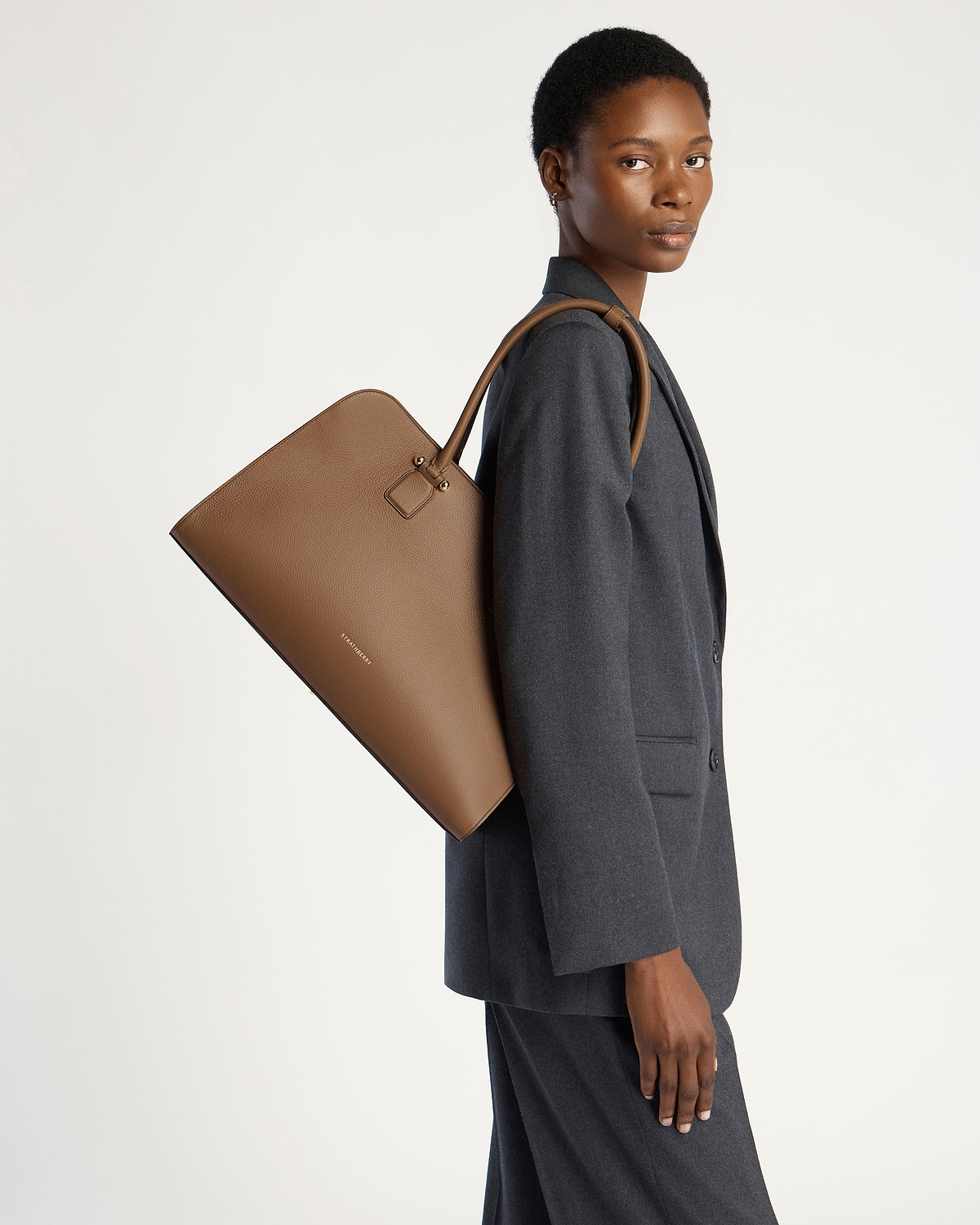 Model carrying a clay leather Strathberry Georgia Maxi tote over her shoulder.
