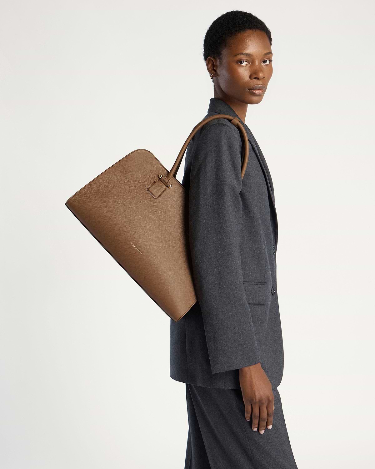Model carrying a clay leather Strathberry Georgia Maxi tote over her shoulder.