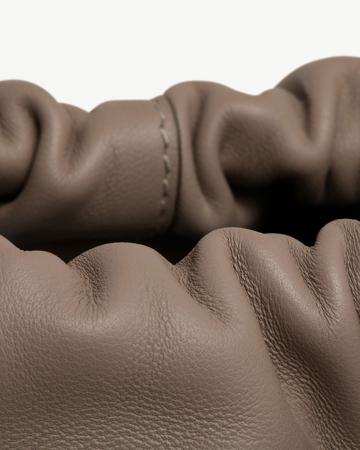 Taupe leather drawstring bag with gathered opening and visible leather grain texture.