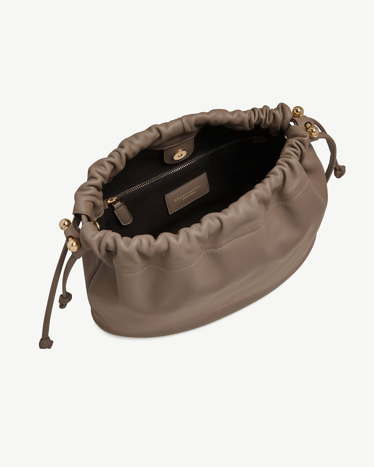 Taupe Strathberry Charlotte Midi drawstring bag open showing interior, zip pocket and gold hardware.