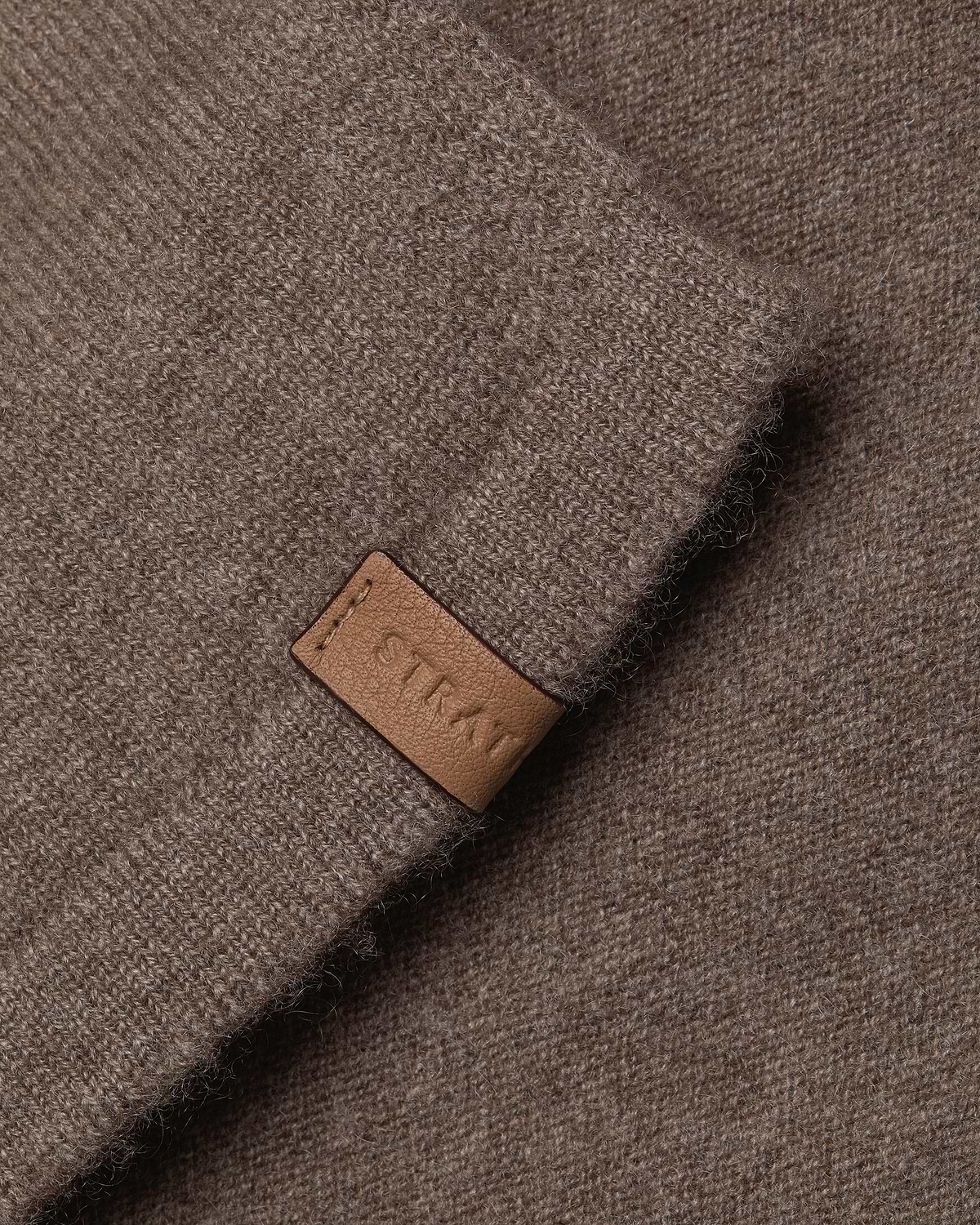 Otter brown cashmere travel wrap, close-up of knitted texture and leather tag