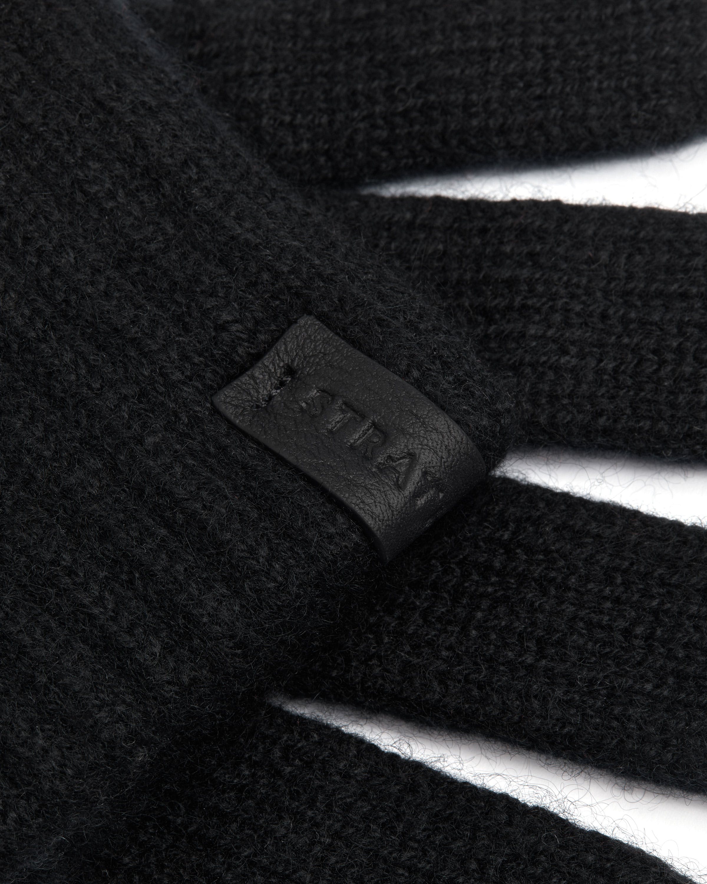 Textured black cashmere glove fabric with embossed Westray leather brand tab.