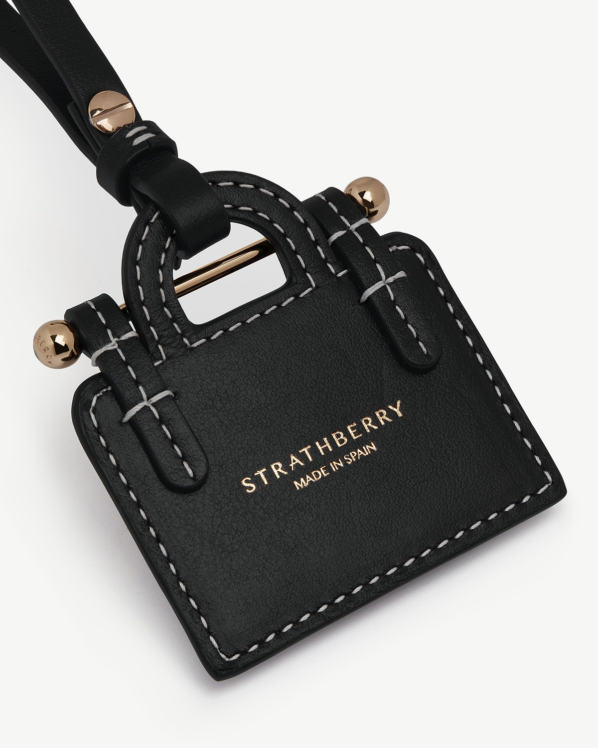 Black leather tote charm with white stitching and gold Strathberry logo.