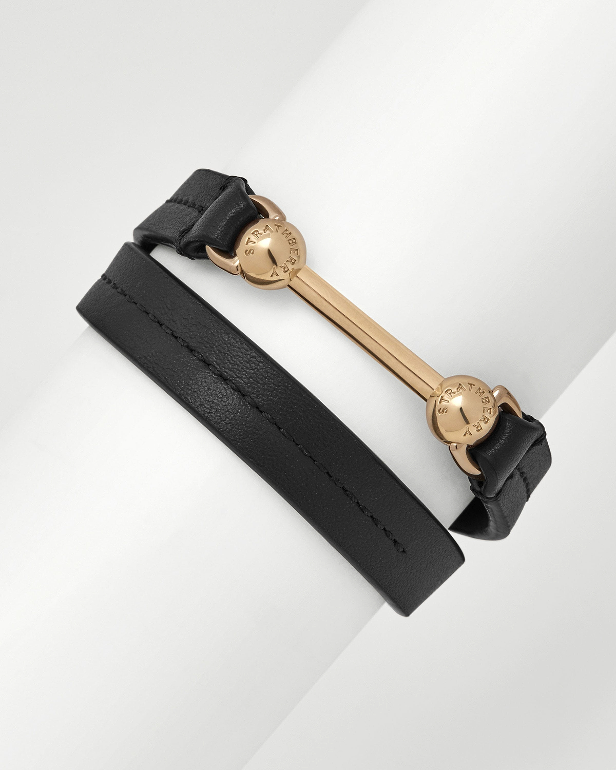 Black double-wrap leather bracelet with gold bar and Strathberry engraved studs.