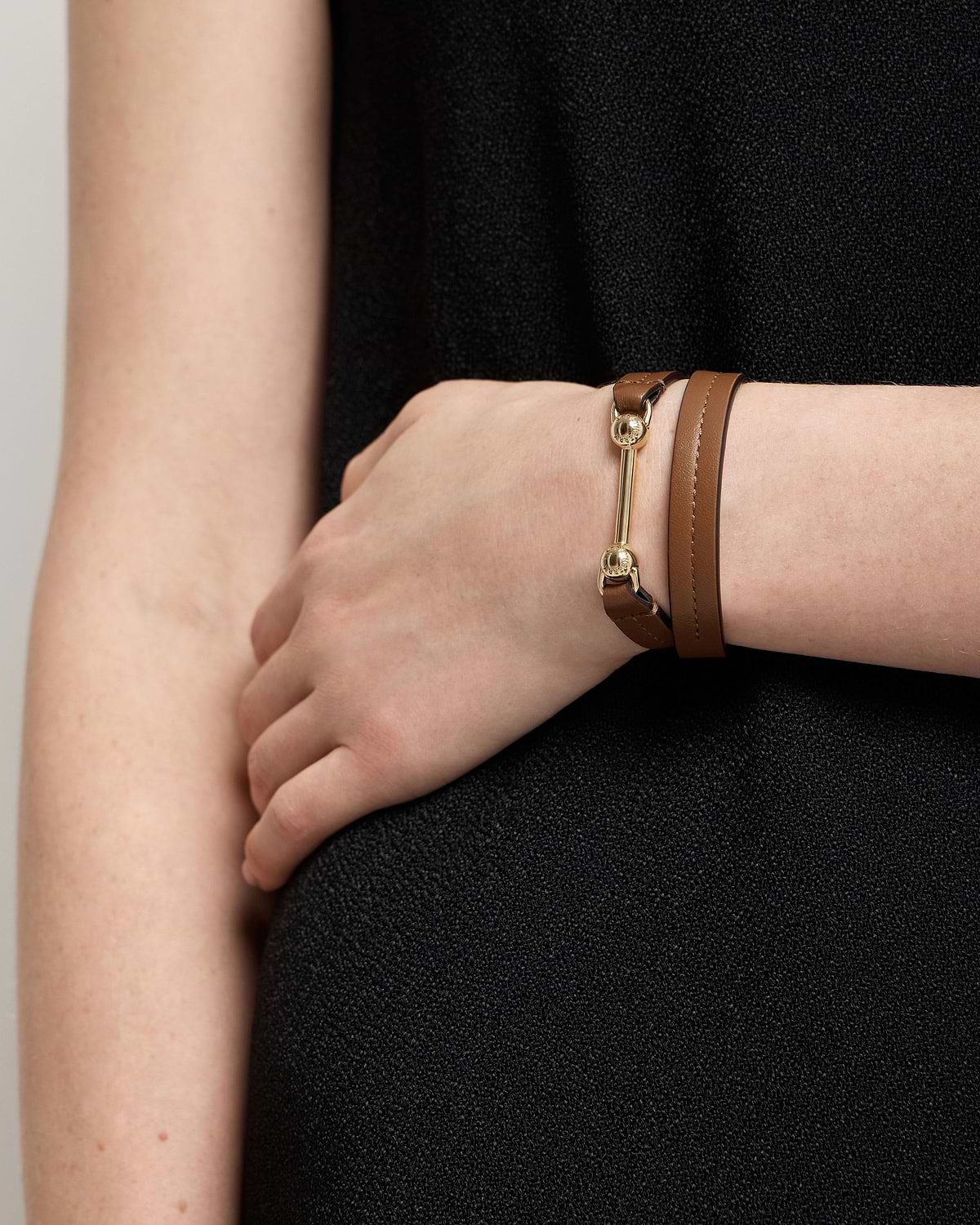 Hazelnut leather double-wrap bracelet with gold bar and round studs on wrist.