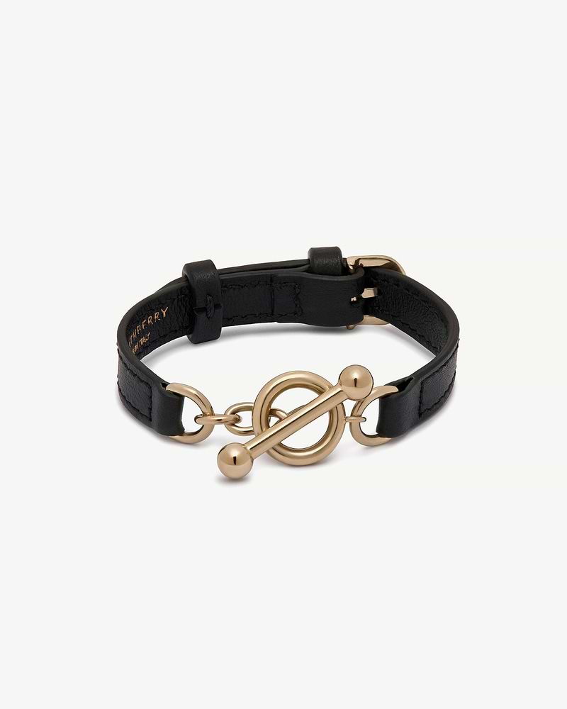 Black leather Strathberry Kite bracelet with gold circular toggle fastener.