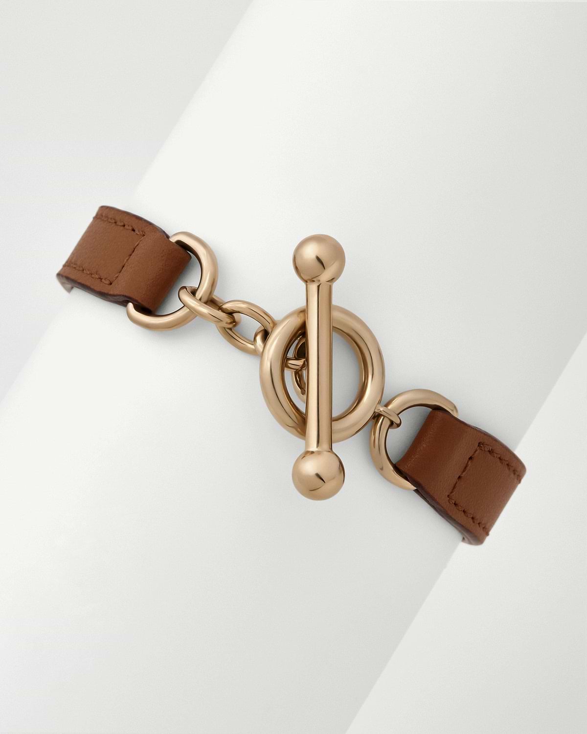 Tan leather kite bracelet with gold-tone toggle clasp on white background