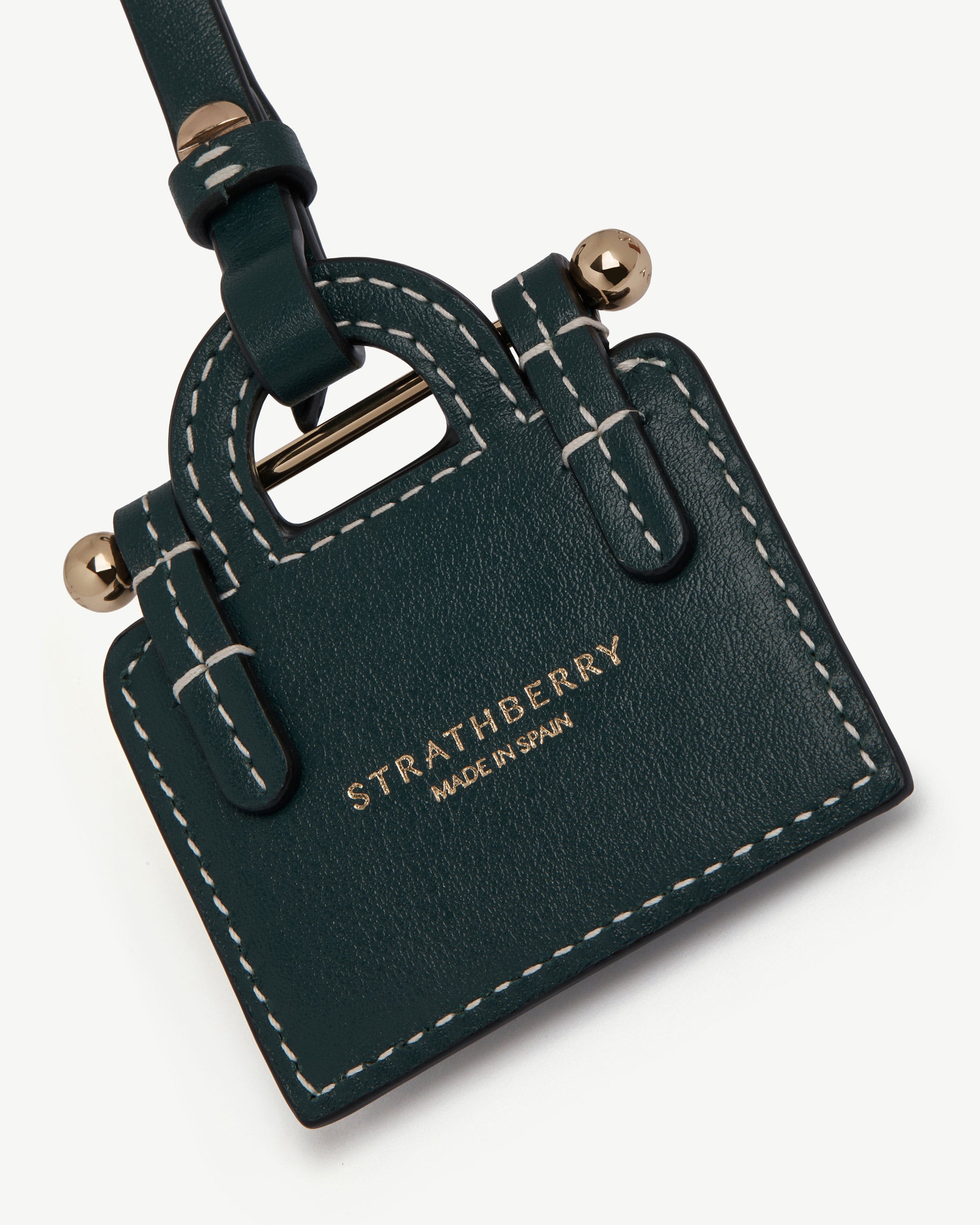 Bottle green Strathberry leather tote charm with white stitching and gold hardware.