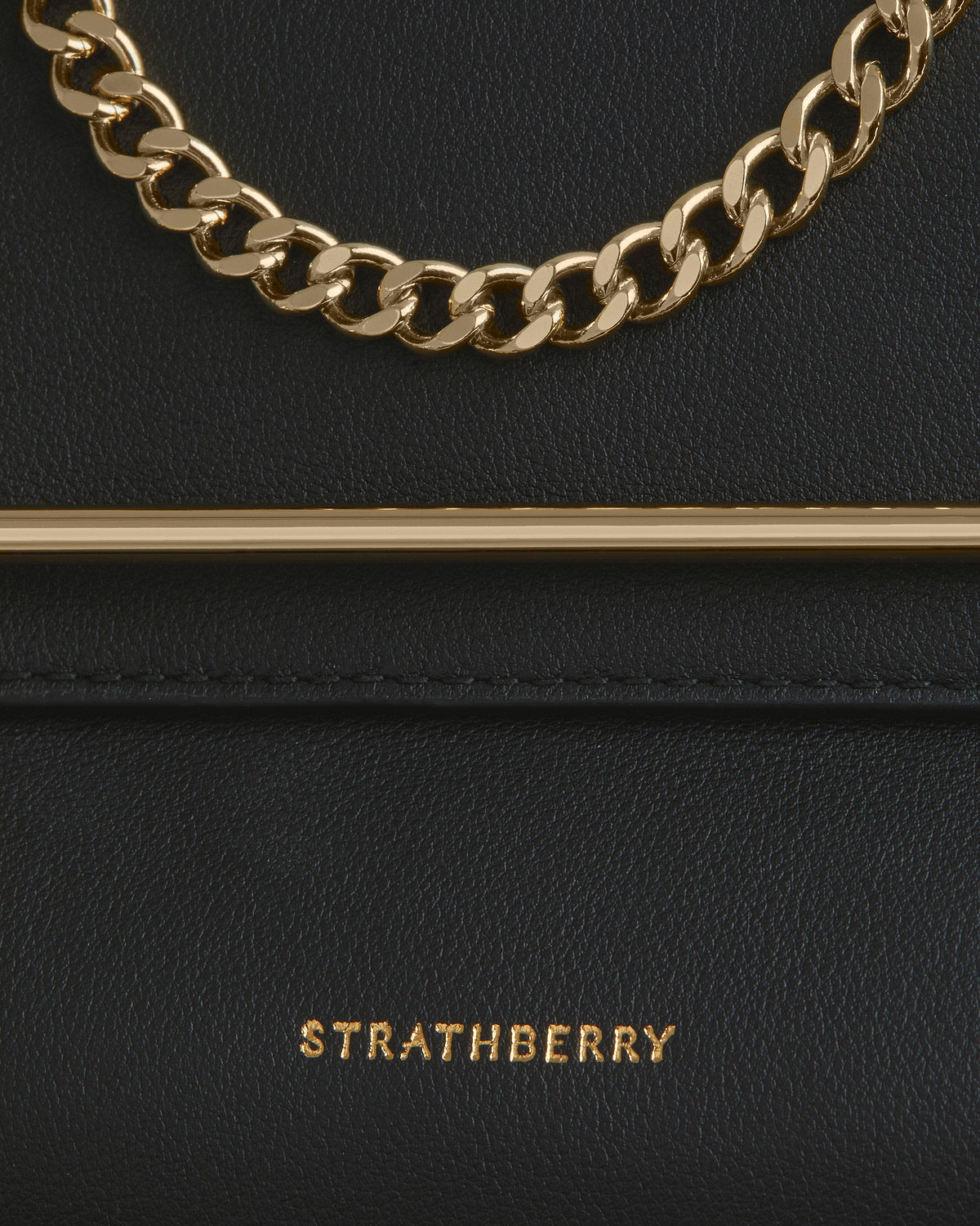 Black leather bag with gold chain, bar trim and Strathberry logo.