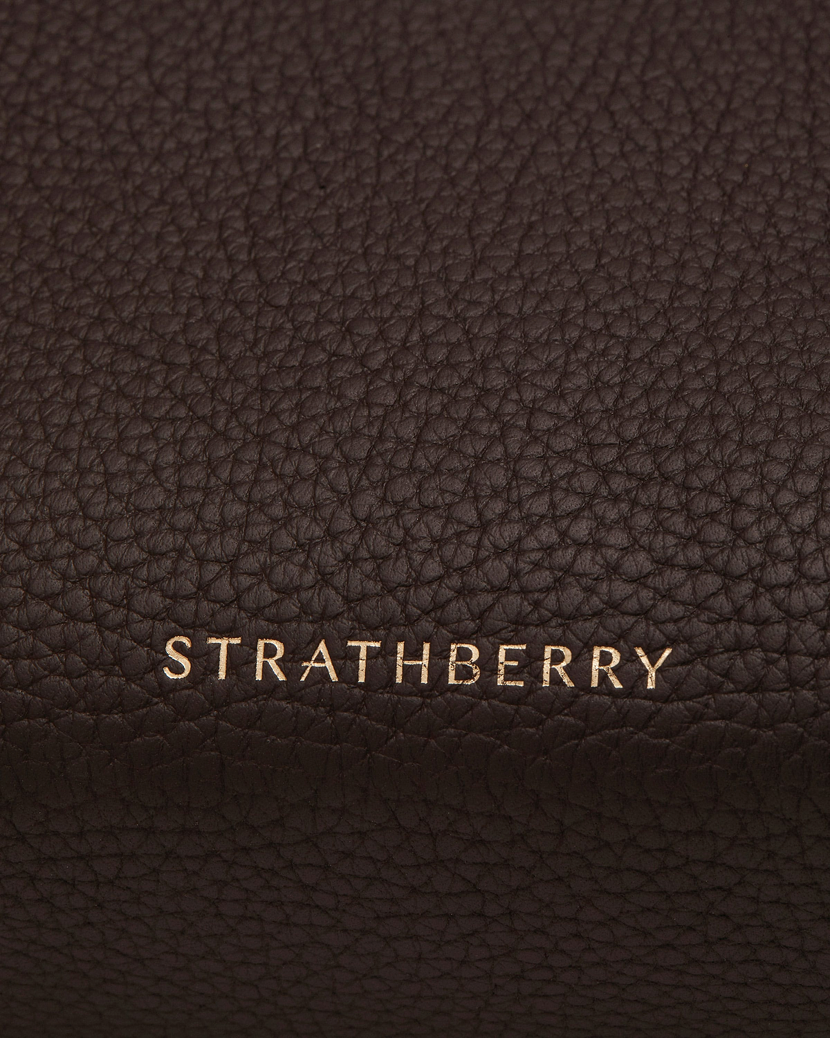 Gold Strathberry logo on espresso pebbled leather of a bag.