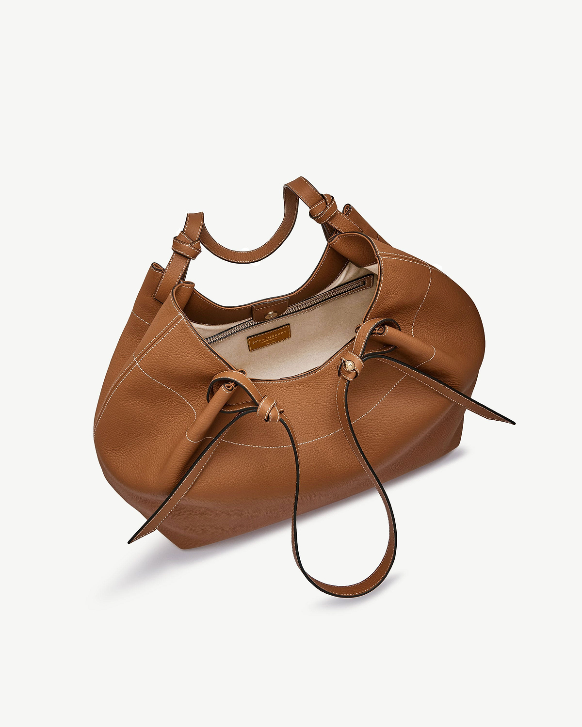 Tan leather Barra tote with white topstitching, drawstring detail and zip pocket, visible Strathberry label