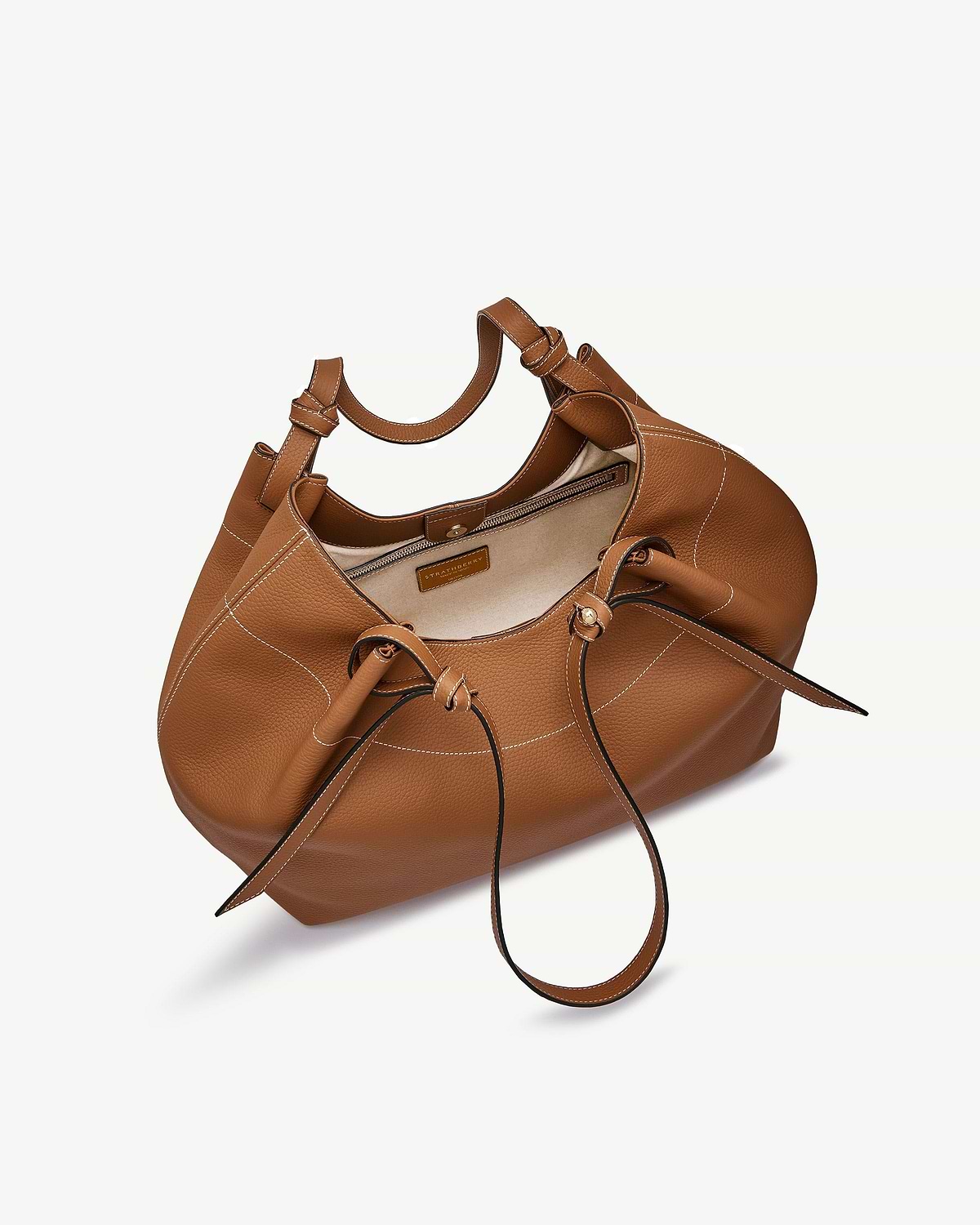 Tan leather Barra tote with white topstitching, drawstring detail and zip pocket, visible Strathberry label