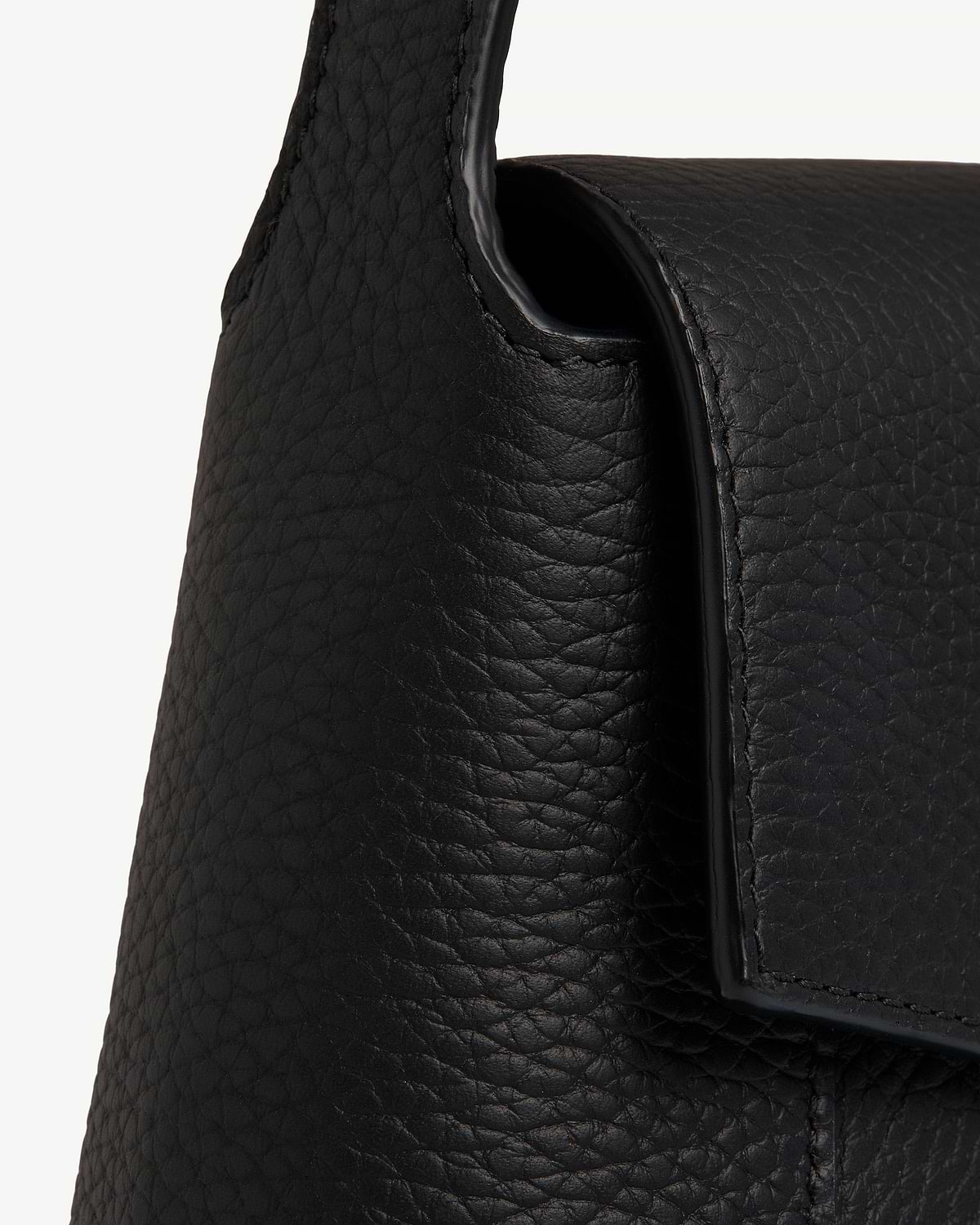 Black pebbled leather shoulder bag showing flap and strap edge.
