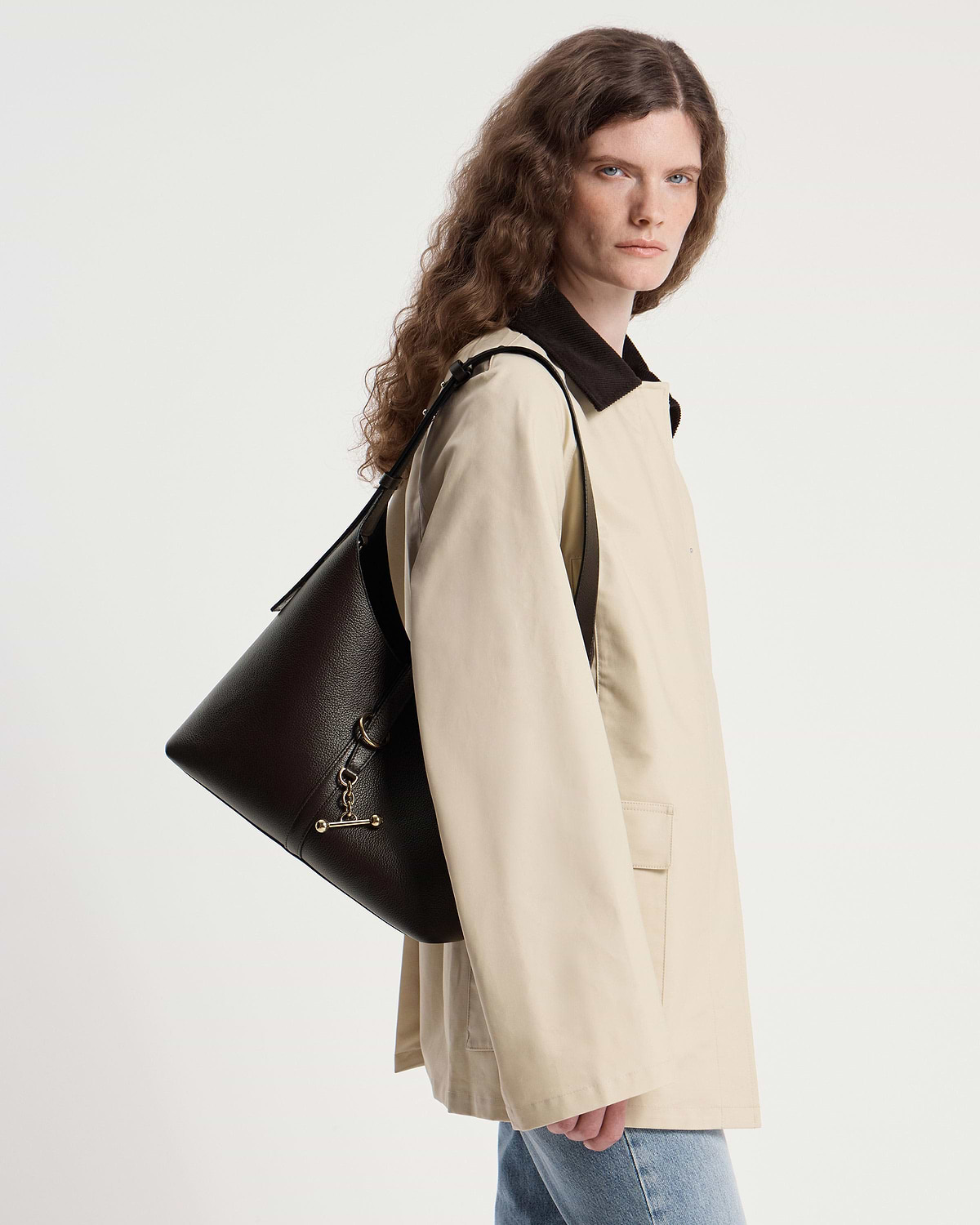 Model wearing a beige coat carrying an espresso leather Kite Hobo bag.