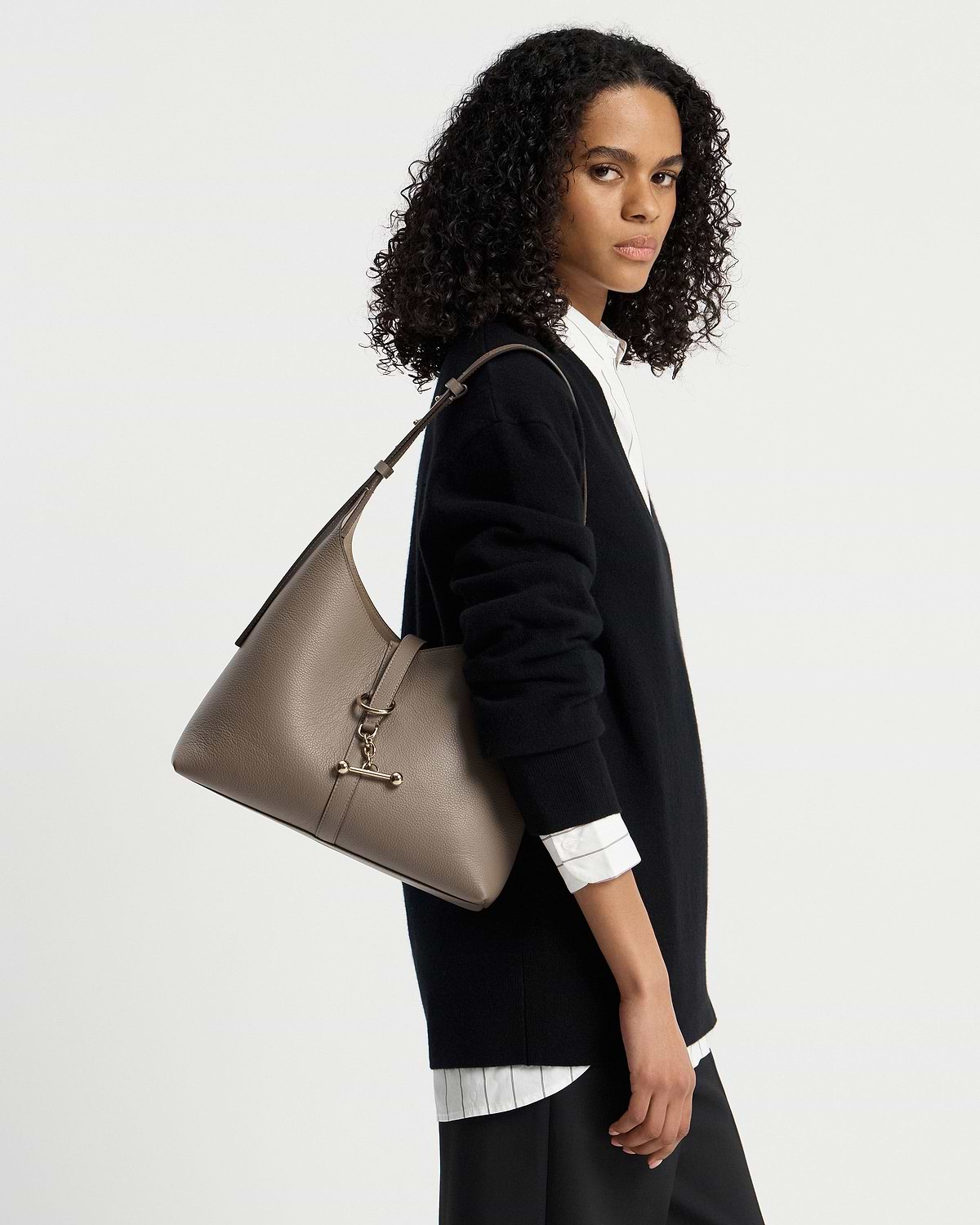 Woman wearing a black sweater carrying a taupe Kite Hobo shoulder bag.