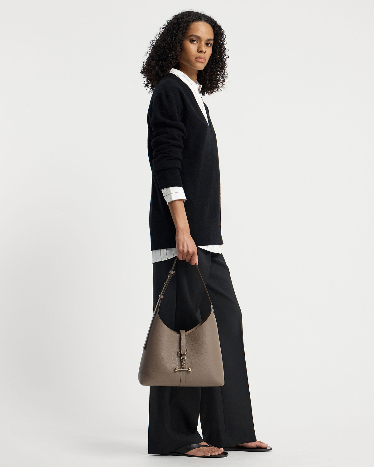 Model holding taupe Kite Hobo shoulder bag with gold T-bar hardware.