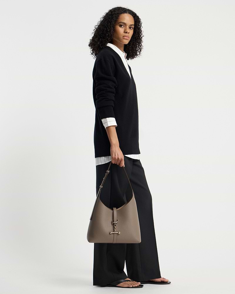 Model holding taupe Kite Hobo shoulder bag with gold T-bar hardware.