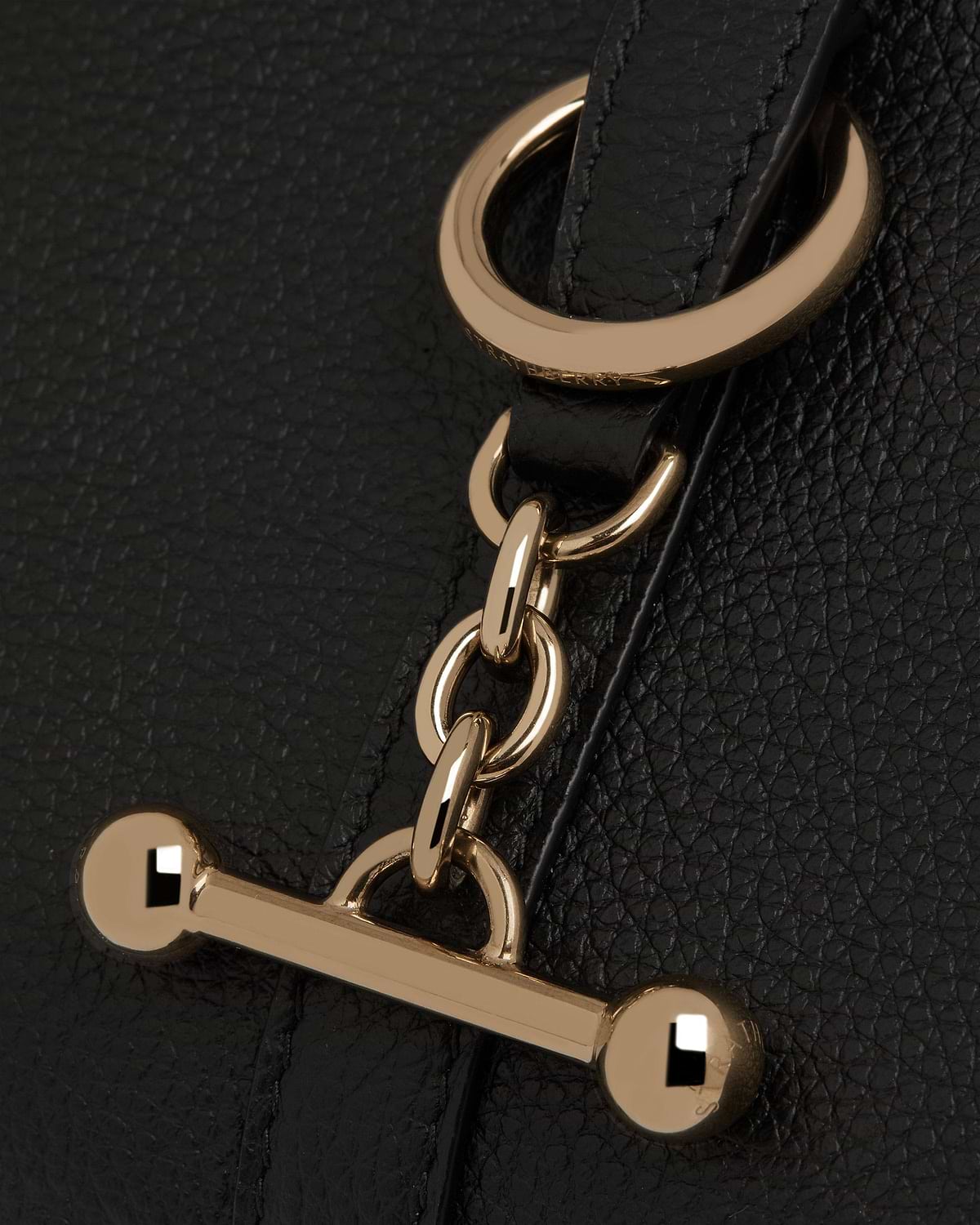 Black pebbled leather close-up of Strathberry gold chain and bar toggle hardware.