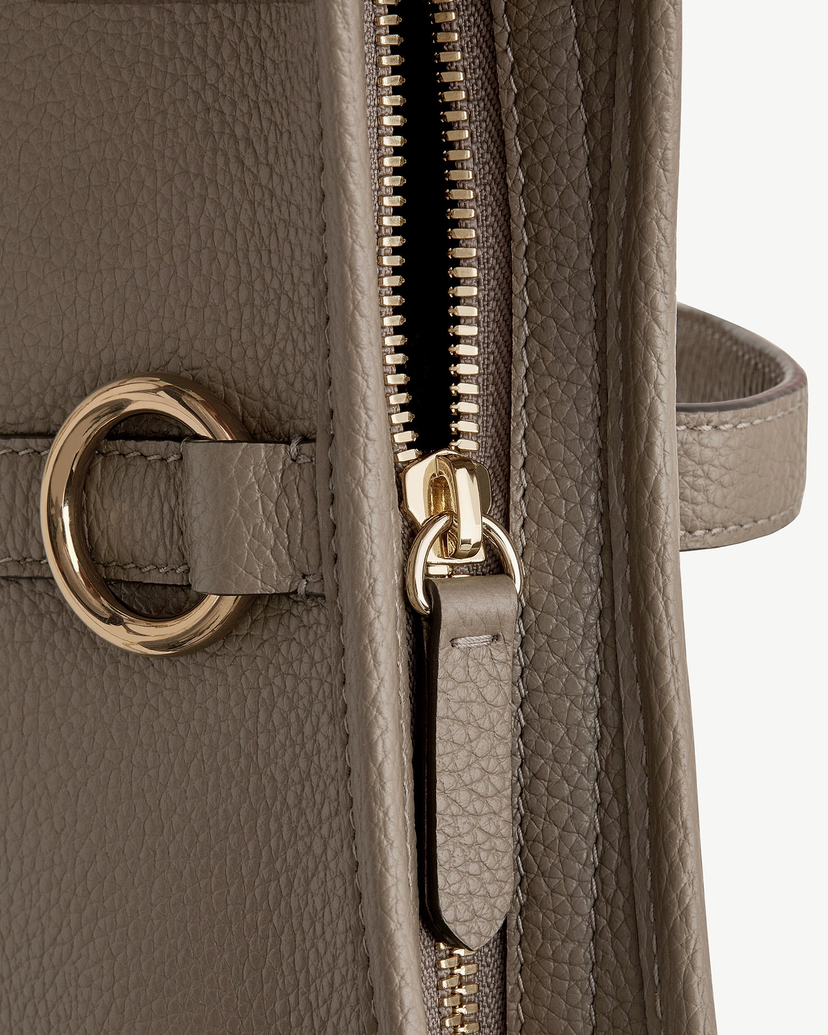 Close-up of taupe pebbled leather handbag zip and gold ring hardware.