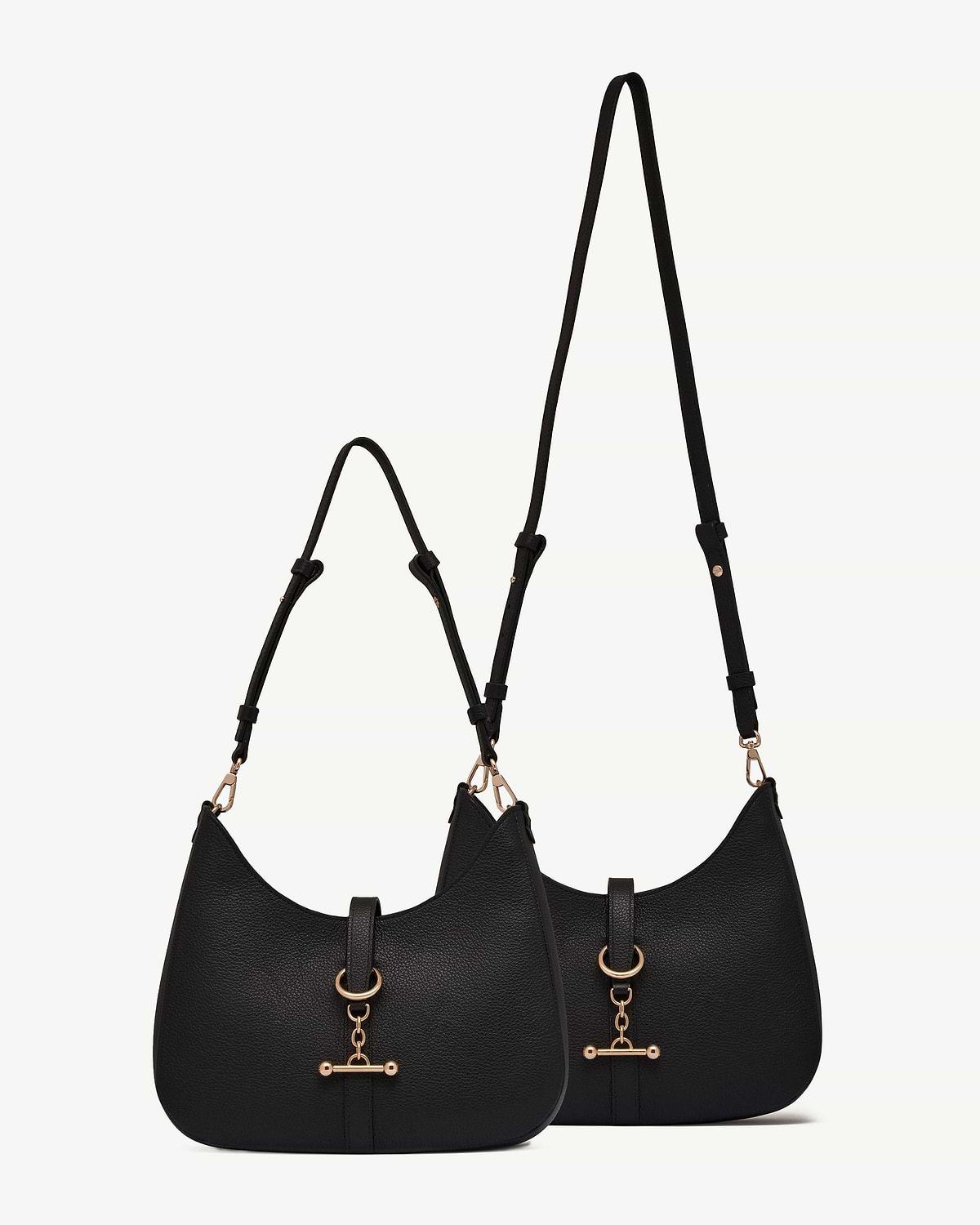 Two black kite sling bags with pebbled leather texture and gold hardware.