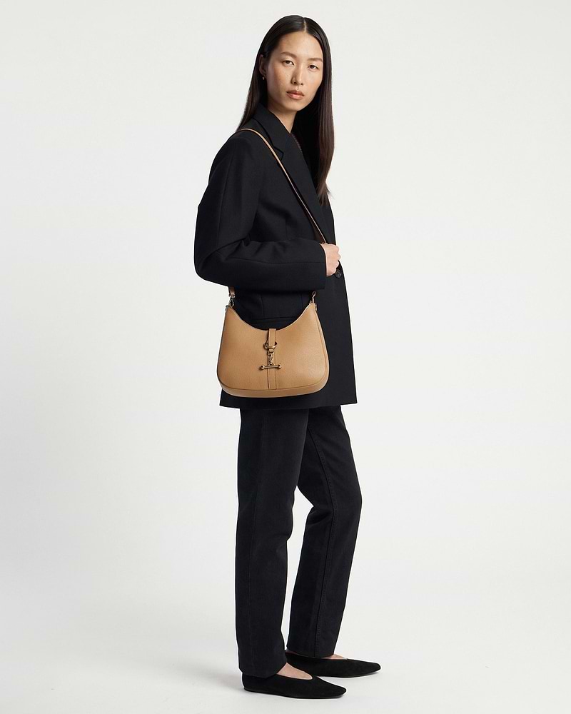 Model wearing caramel kite sling bag with shoulder strap and black blazer.