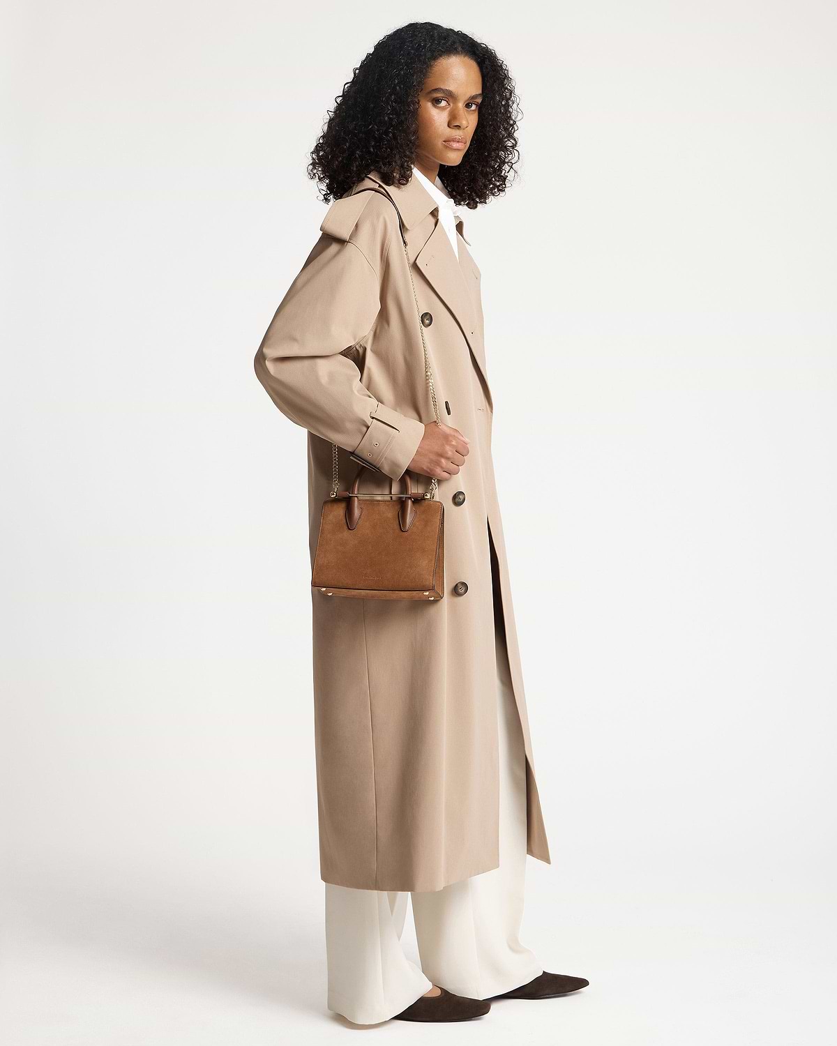 Model wearing tan suede mini tote with chain strap and top handles.
